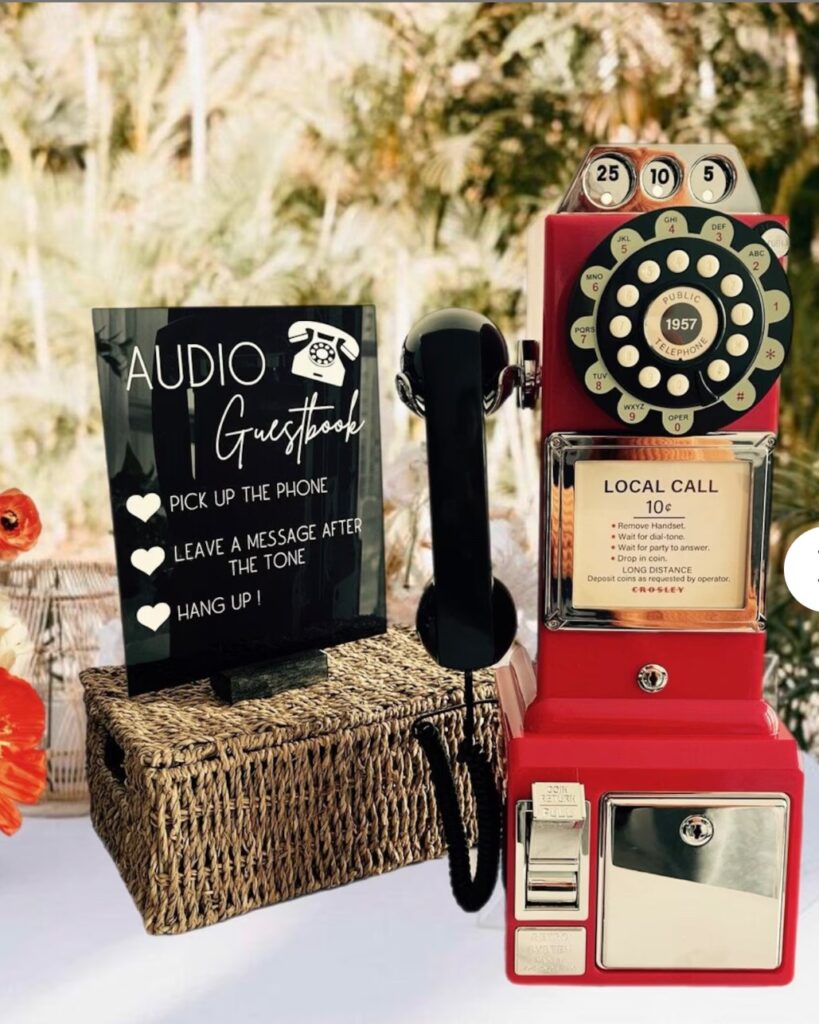 A red vintage-style telephone placed on a wicker basket next to a sign instructing guests to leave audio messages after the tone.